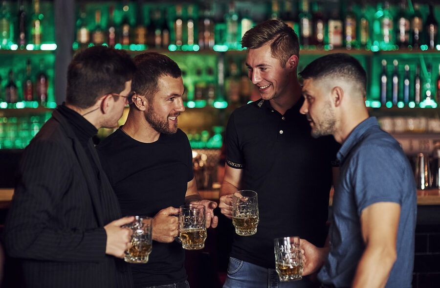 Warm atmosphere. Friends resting in the pub with beer in hands. Having conversation